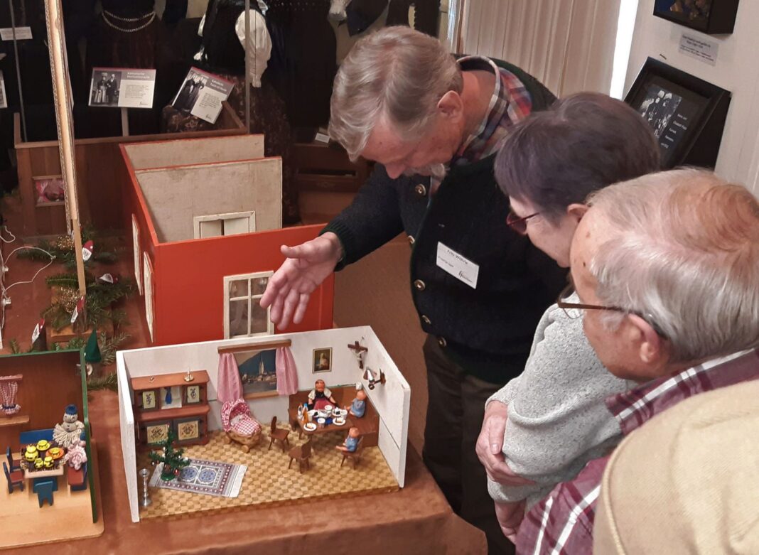 Fritz Wöhrle (hinten) erläutert seinen Gästen die Besonderheiten der ausgestellten Puppenstuben, Puppenküchen und Kaufmannsläden. Foto: Alfred Moosmann