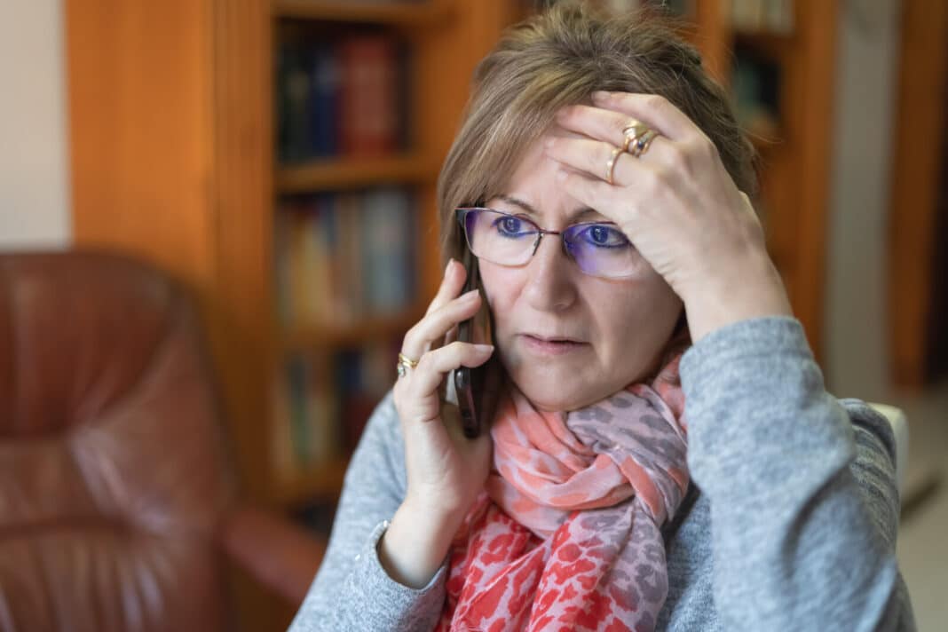 white woman talking on the phone and receiving bad news with a worried face.